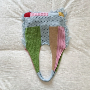 Detail of artistic patchwork knit tote with fringe edges and varied stitch patterns