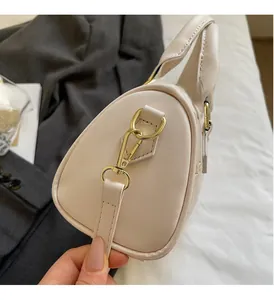 Detail of high-gloss gold hardware and textured cream Boston bag for women