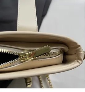 Gros plan détaillé sur la fermeture éclair dorée et le cuir synthétique beige du sac seau