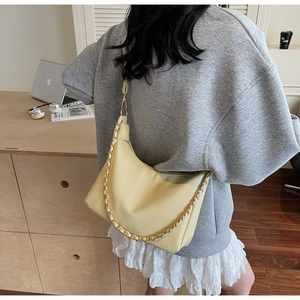 Detail of light yellow crescent hobo bag with litchi texture and gold chain strap