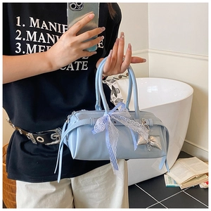 Détail du sac cylindrique bleu clair avec nœud en dentelle et pendentif oreiller argenté