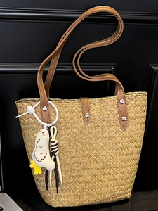 Handwoven straw tote bag with brown leather handles and a cute white chick charm