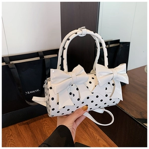 Détail du sac cylindrique blanc à pois noirs avec nœuds et bandoulière amovible