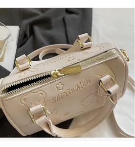 Close-up of beige leather Boston bag showing smooth gold zipper and embossed bear patterns