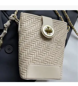 Gros plan du sac bandoulière beige tissé avec fermoir rotatif doré et bandoulière en chaîne