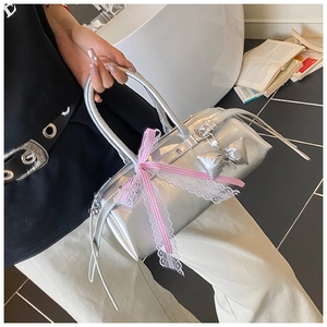 Détail du sac à main argenté métallisé avec nœud en dentelle rose et breloque papillon