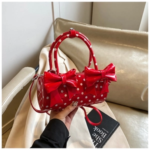 Détail du sac à main rouge à pois en cuir verni avec nœuds et ferrures argentées