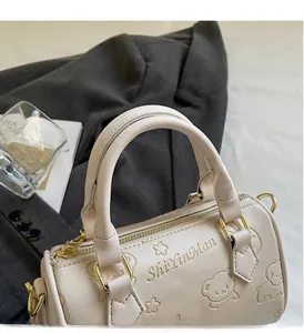 Detail of light pink Boston bag featuring embossed cartoon animals and golden hardware