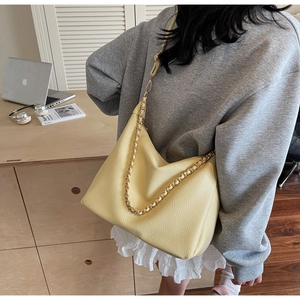 Detail of soft yellow hobo bag with pebble leather texture and braided chain strap