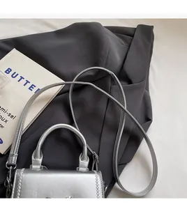 Dettaglio della mini borsa a tracolla argento metallizzato con manici e cuciture fini