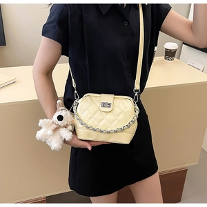 Detail showing cream quilted handbag with chunky silver chain and cute teddy bear charm