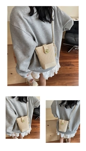 Vue détaillée du sac seau tressé beige avec fermoir anneau doré et bandoulière chaîne