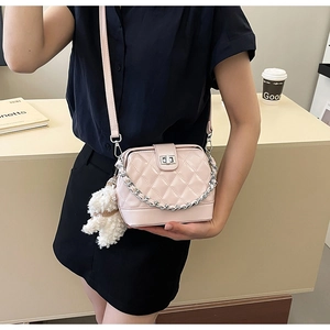 Close-up of pink quilted crossbody bag with silver chain strap and plush bear charm