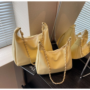 Detail of two yellow leather dumpling bags with chain straps in large and small sizes