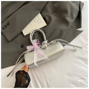 Détail du mini sac à main argenté effet miroir avec nœud en dentelle et pendentif coeur