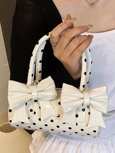 Sac à main cylindrique blanc à pois avec grands nœuds et finition en cuir verni brillant