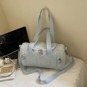 Detail of light blue gym bag with nylon texture, zippers, and cross-body strap