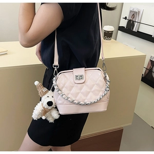 Detail view of pink quilted handbag with silver chain and cute plush puppy charm
