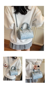 Detail view of small light blue Boston bag with cartoon bear print and adjustable strap