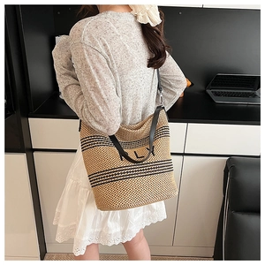 Détail du sac cabas en paille tissé à la main avec rayures noires et broderie KLY tendance