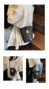 Vue détaillée du sac seau tissé noir avec une boucle circulaire en métal doré brillant