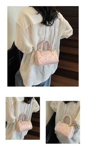 Detail of pink Boston bag showing cartoon bear embossing and adjustable strap on a model