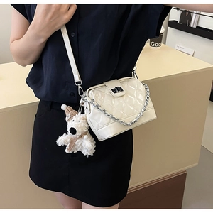 Quilted white crossbody bag with silver chain and cute teddy bear charm on model
