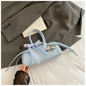 Détail d'un sac à main bleu clair verni avec nœuds en dentelle et pendentif étoile argenté