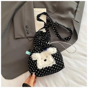 Dettaglio della borsa a secchiello nera a pois con patch animale in peluche bianco e coulisse