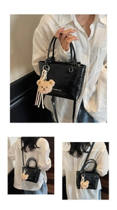 Detail view of black textured mini tote bag with cute brown bear charm and crossbody strap