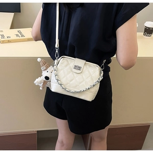 Close-up of a white quilted chain bag featuring a silver twist lock and a cute plush puppy charm