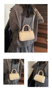 Detailed view of beige Boston bag with embossed cartoon bear and adjustable shoulder strap