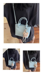Close-up of light blue litchi pattern mini tote with knot handle and bear charm detail