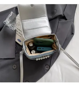 Dettaglio della mini borsa a tracolla argento e denim che mostra la capienza interna