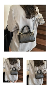 Detail of black Boston bag featuring embossed bear patterns and gold metal hardware