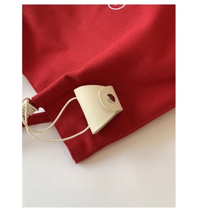 Close-up of red canvas tote with cream leather handle and silver snap button detail