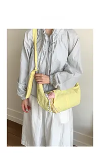 Detail der hellgelben Nylon-Tasche mit Herzanhänger und verstellbarem Schultergurt