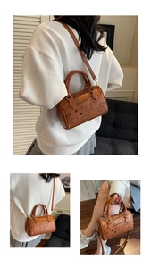 Close-up of brown Boston bag with cartoon bear print and adjustable gold hardware strap