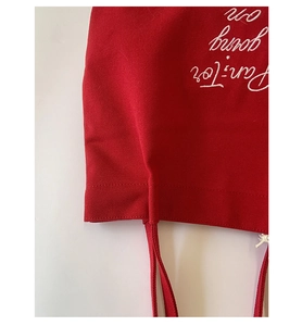 Detailed close-up of white embroidery and durable stitching on a red canvas tote bag