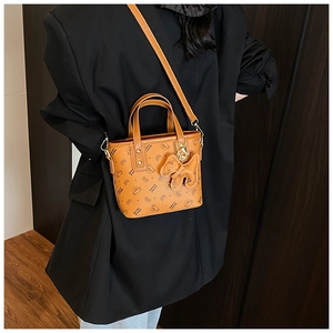 Brown handbag with bear print and cute charm shown on a black blazer outfit
