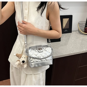 Detailed view of silver quilted crossbody bag with metal chain and cute puppy charm