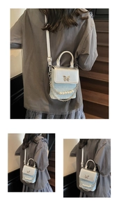 Detail view of mini crossbody phone bag featuring pearl chain and silver butterfly buckle
