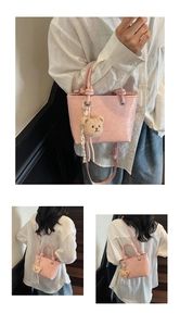 Detail view of pink patent leather tote bag with crinkle texture and plush bear charm