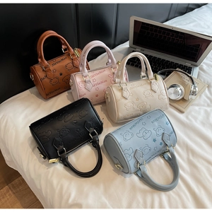 Flat lay of colorful mini Boston bags with bear embossing on a cozy bed background