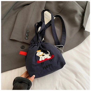 Dettaglio della borsa a secchiello in tela blu navy con ricamo di cucciolo e cinturini rossi