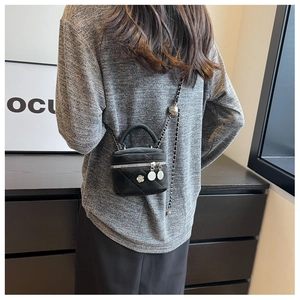 Detalle de un mini bolso vanity negro acolchado con cadena de plata usado por una modelo