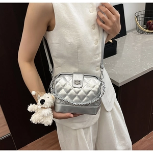 Detail of silver quilted chain bag with a cute white plush puppy charm pendant