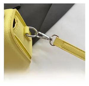 Detail of silver metal hook and yellow litchi grain leather strap with precise stitching