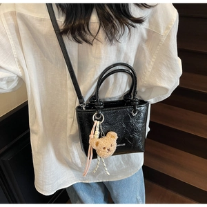 Mini black tote bag with glossy wrinkled texture and a cute teddy bear charm