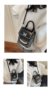 Detail view of black sequin mini crossbody bag with pearl trim and silver butterfly accent